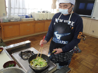 野菜を炒める児童の画像