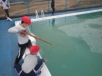 熊手レーキで氷を引き寄せる児童の画像