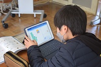 プログラムをタブレット画面で確認する児童の画像
