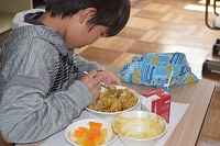 カレーをご飯と混ぜる児童の画像