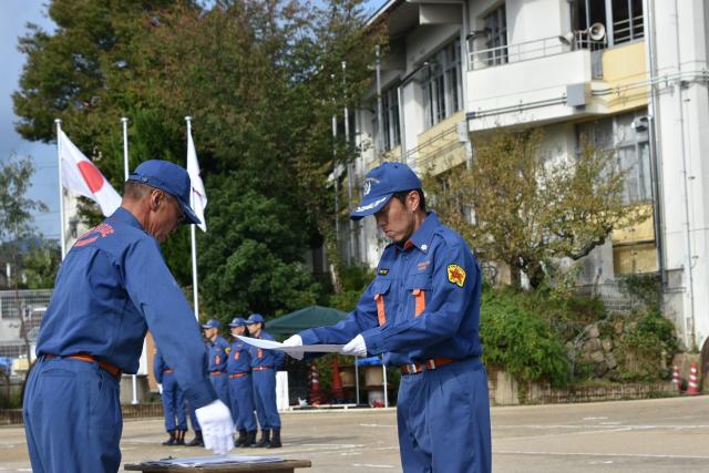 礼式訓練（室外の物品授受）を行う畑野分団員の画像