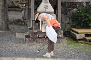 神社の前でごみを拾う人