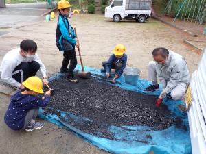 登校した児童が炭を粉にする作業をする画像