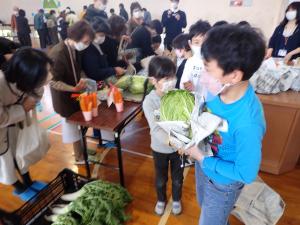 新聞紙で野菜をくるむ児童の画像