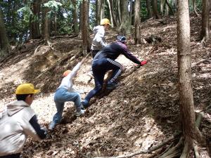 土手の滑り台を登る児童らの画像