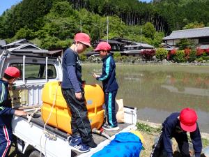 効率よく泥を落とせるように給水車？を準備配水する児童の画像