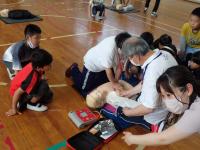 AEDを装着する様を見学する児童らの画像