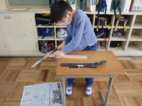 机を台に鋸引きする児童の画像