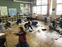 床に座し毛筆する児童らの画像