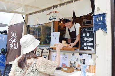 お客さんにコーヒーを渡す店主